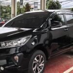 Black Toyota SUV parked in a covered parking area with wet red-tiled floor and white lines.