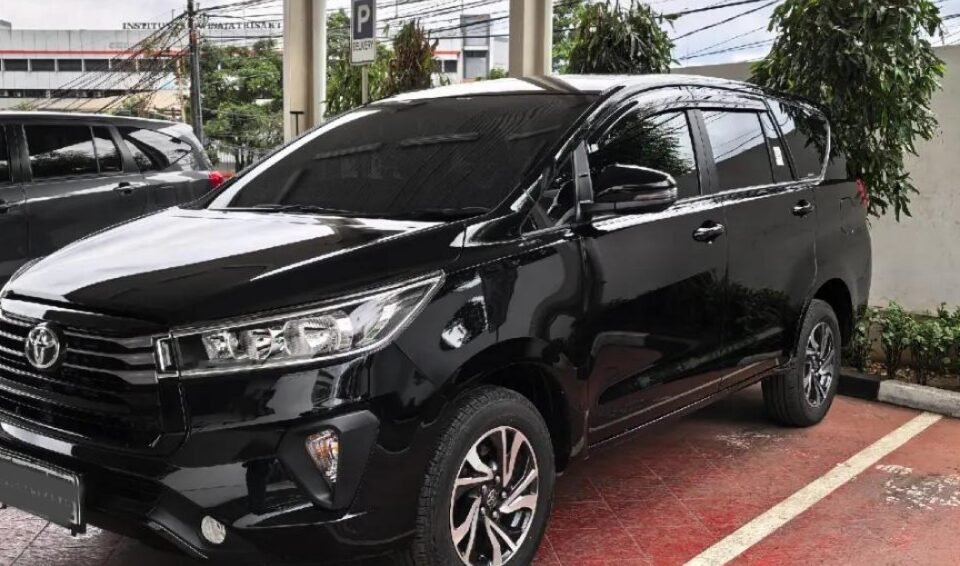 Black Toyota SUV parked in a covered parking area with wet red-tiled floor and white lines.