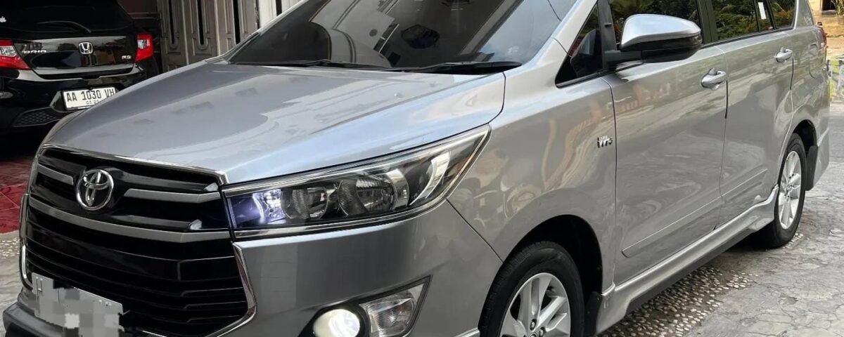 Silver Toyota minivan parked in a residential driveway, front-left angle of the vehicle