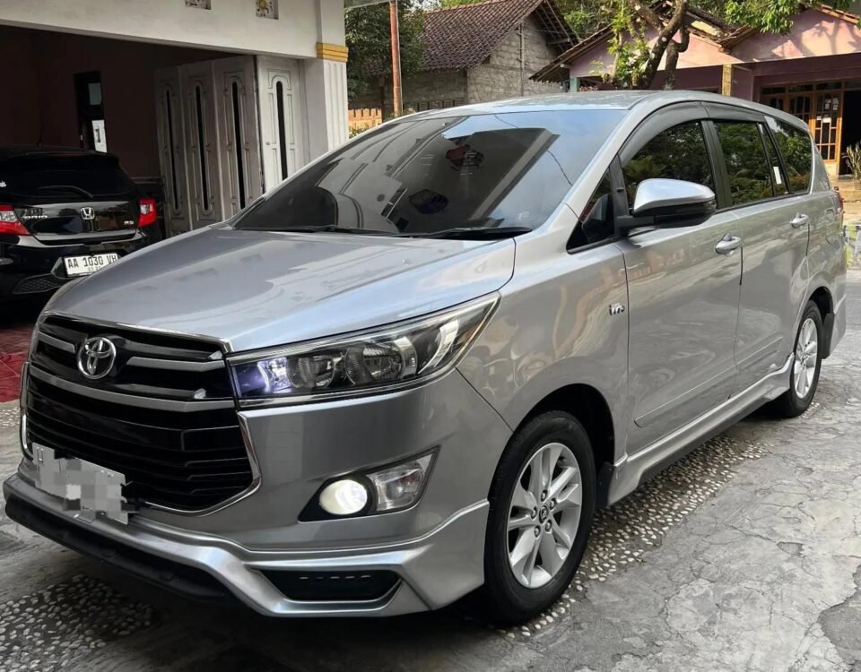 Silver Toyota minivan parked in a residential driveway, front-left angle of the vehicle