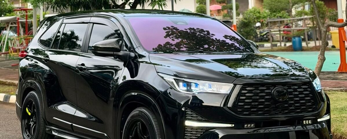 Black SUV parked on a street, glossy finish reflecting surrounding trees with a green urban backdrop behind it.