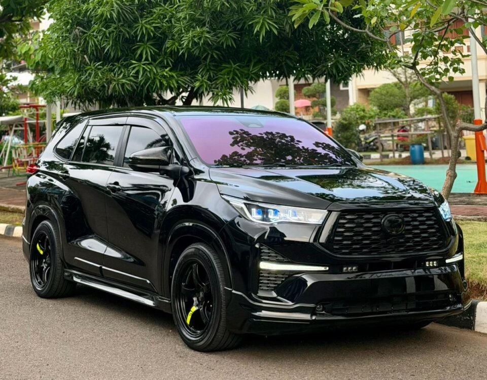 Black SUV parked on a street, glossy finish reflecting surrounding trees with a green urban backdrop behind it.