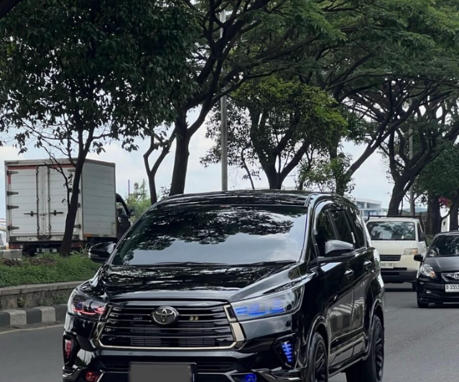 Black Toyota SUV driving on a tree-lined city street with other cars in the background
