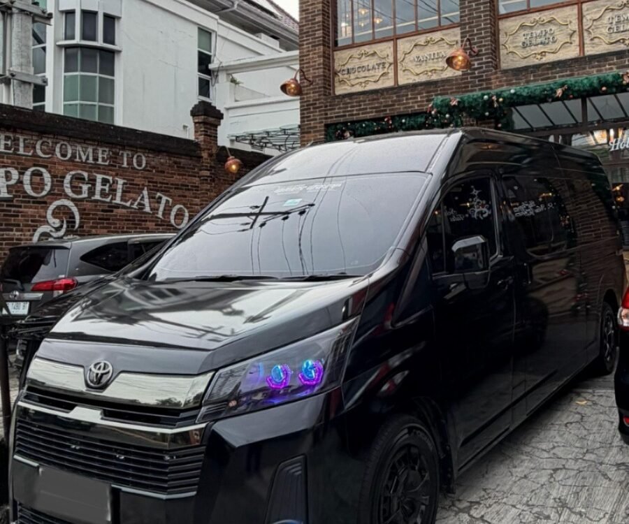 Black Toyota van parked in front of a brick gelato shop with a large clock window.