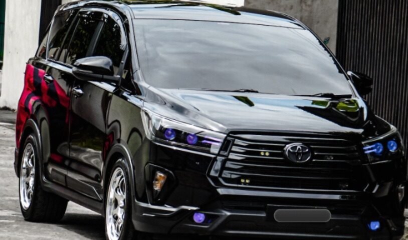 Black Toyota SUV parked on a street with a white wall and large green banana leaves in the background.