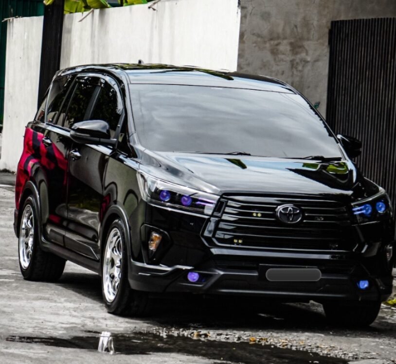 Black Toyota SUV parked on a street with a white wall and large green banana leaves in the background.