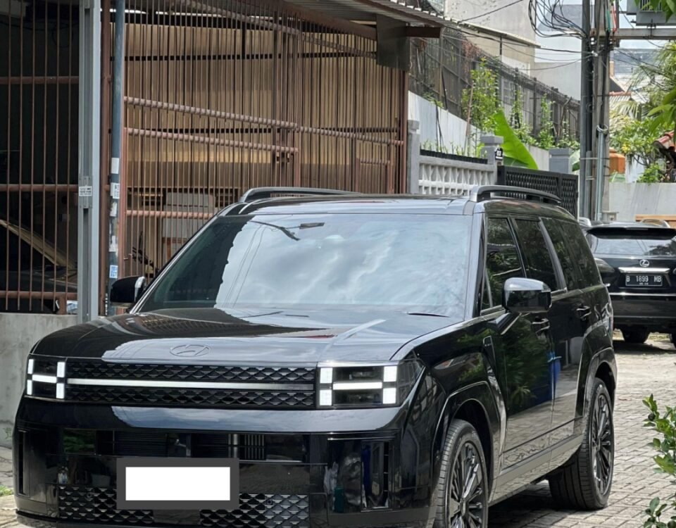 Front three-quarter view of a black SUV parked on a brick driveway with a gated building in the background and overhead power lines.