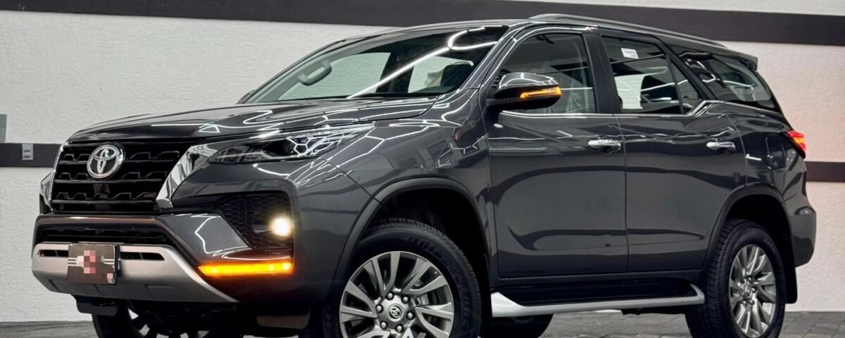 Showroom scene with a dark-colored Toyota SUV, close-up of front and side, glossy reflections and neon ceiling lights above