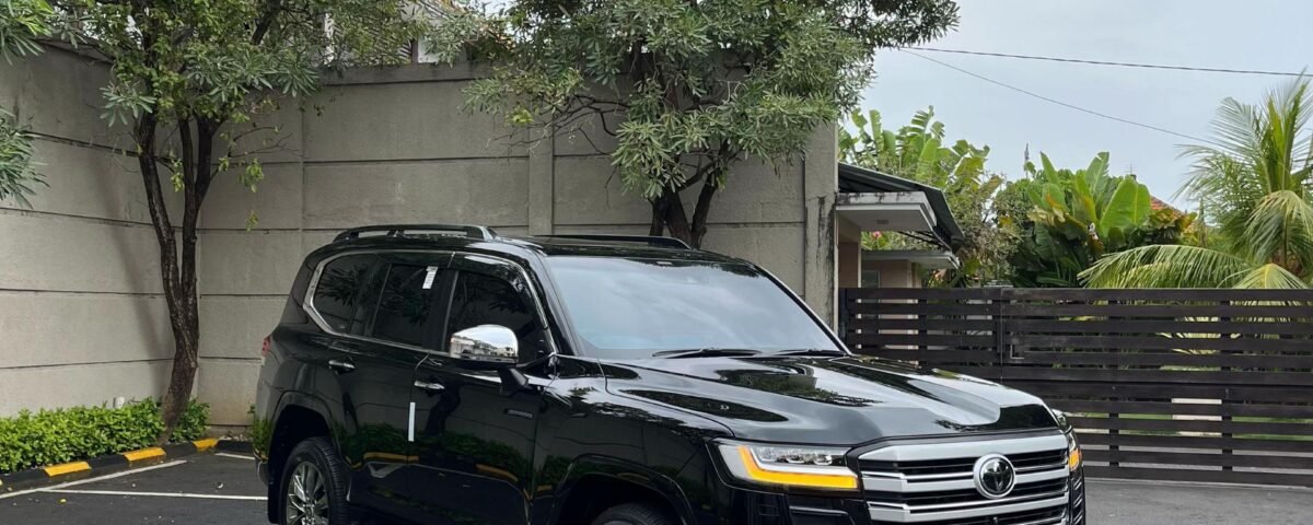 Black SUV parked in a parking lot beside a gray concrete wall under a cloudy sky on an overcast day.