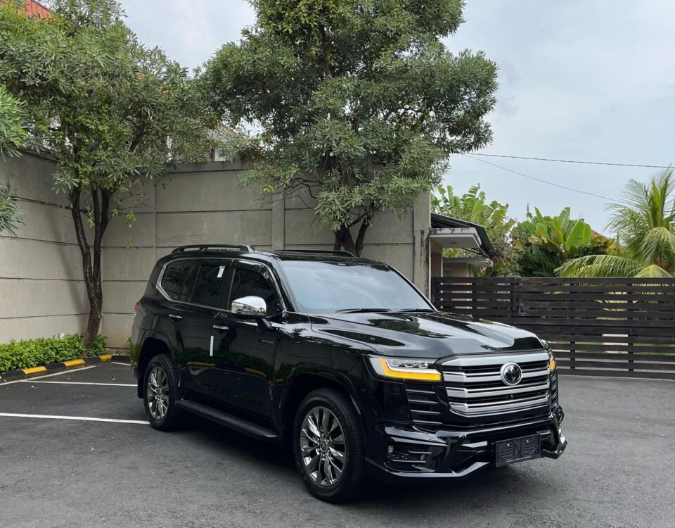 Black SUV parked in a parking lot beside a gray concrete wall under a cloudy sky on an overcast day.