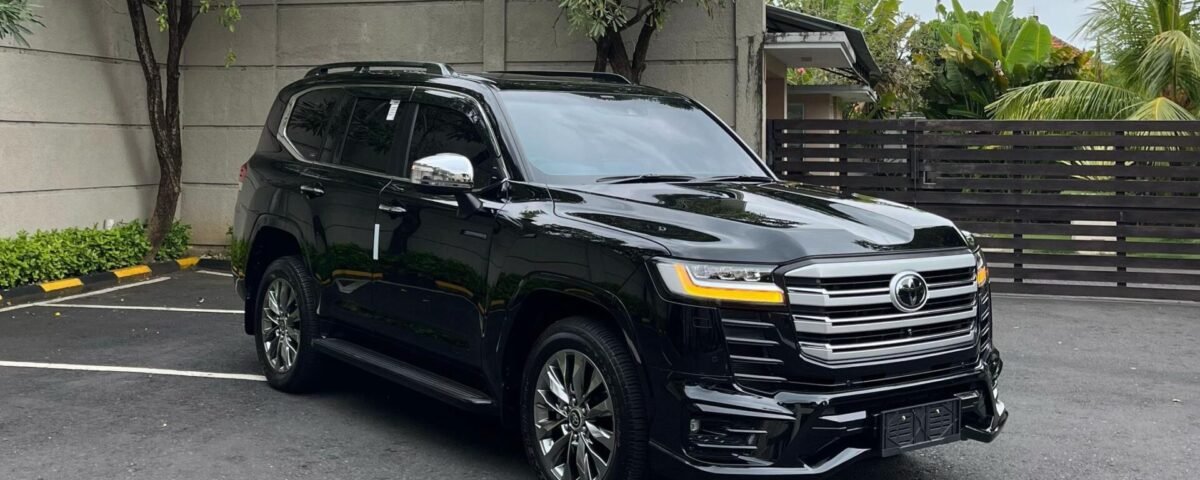 Black SUV parked in a parking lot beside a gray concrete wall under a cloudy sky on an overcast day.