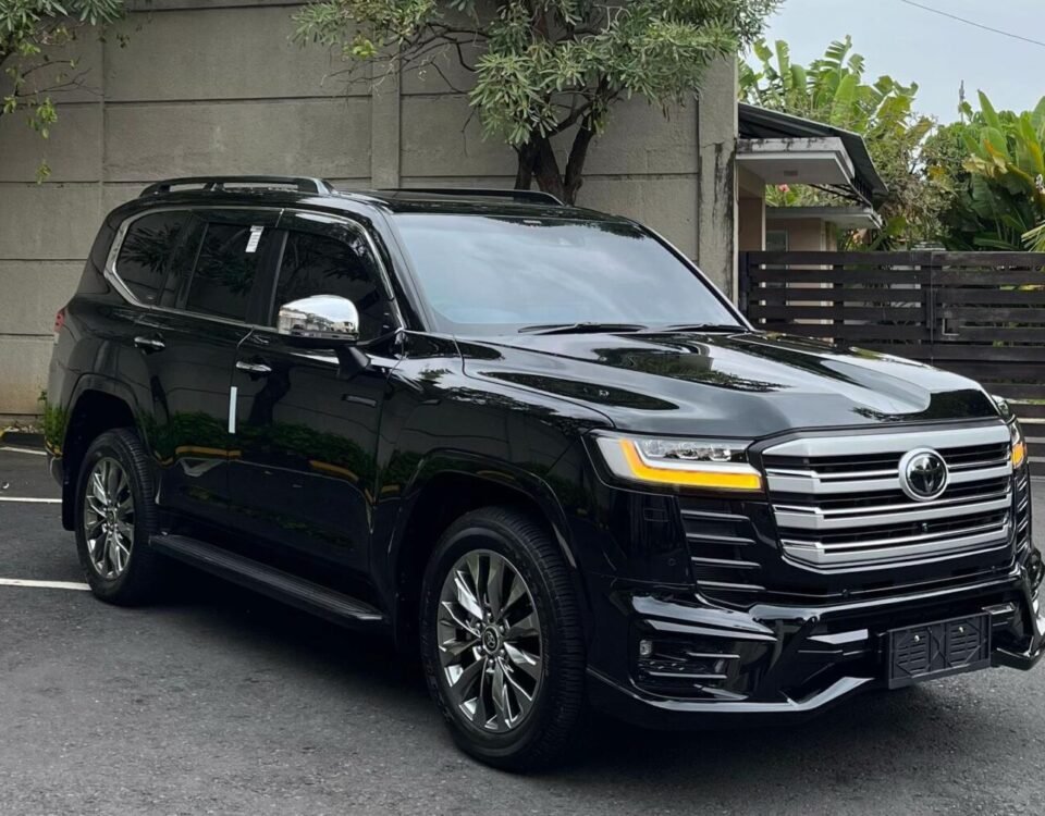 Black SUV parked in a parking lot beside a gray concrete wall under a cloudy sky on an overcast day.