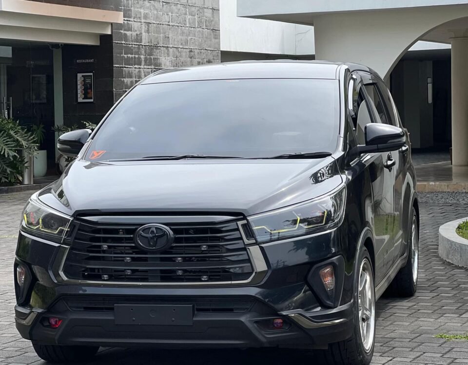 Front view of a dark gray Toyota SUV parked on a brick driveway in front of a modern building complex