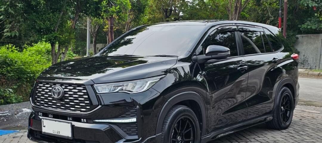 Black Toyota SUV parked on a brick-paved street with green trees in the background.