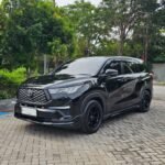 Black Toyota SUV parked on a brick-paved street with green trees in the background.