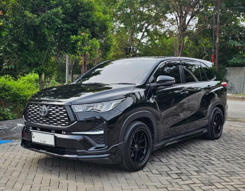 Black Toyota SUV parked on a brick-paved street with green trees in the background.