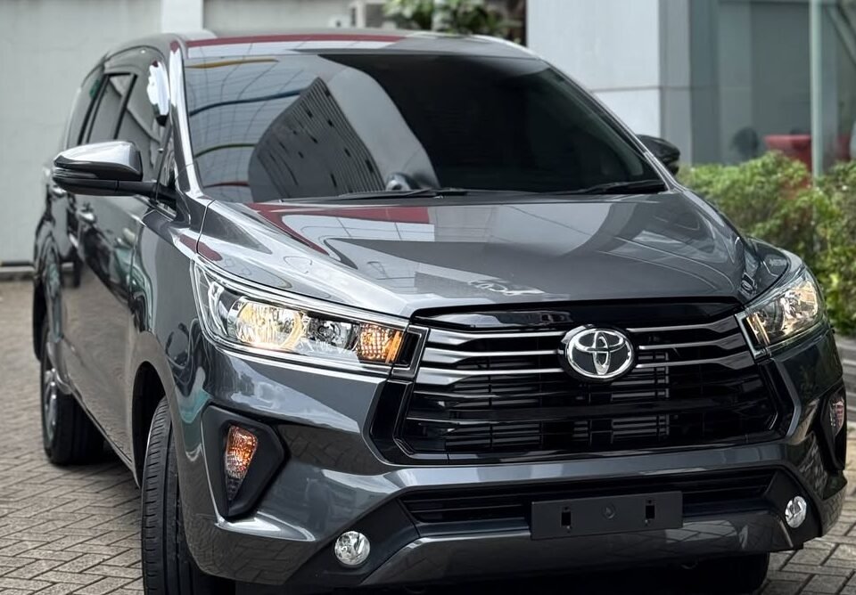 Gray Toyota SUV parked diagonally in front of a modern glass building with a red wall in the background