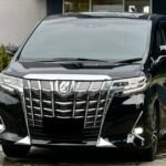 Black luxury minivan parked in front of the Topgolf Jakarta entrance/line of the building.