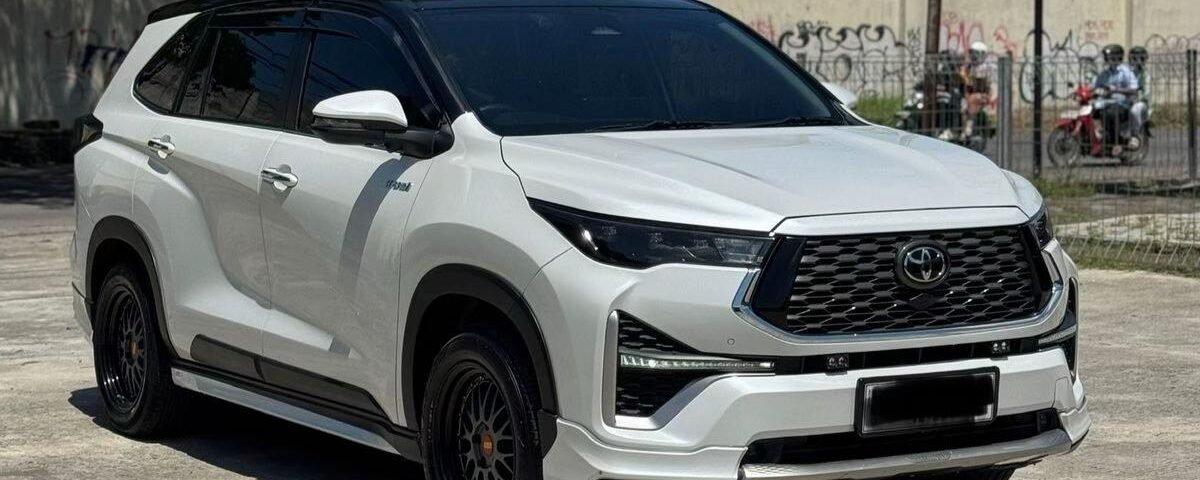 Front three-quarter view of a white Toyota SUV with black accents and dark wheels parked on a sunny lot.