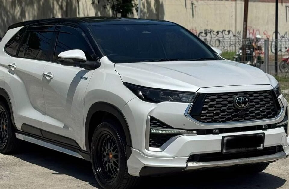 Front three-quarter view of a white Toyota SUV with black accents and dark wheels parked on a sunny lot.