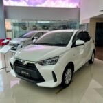 SaveTikTokto_7494885108328025399_1 - Dyantransport White compact SUV on display in a bright car showroom, front grille and badge visible (Agya model)