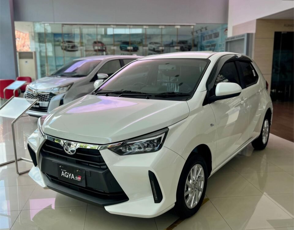 White compact SUV on display in a bright car showroom, front grille and badge visible (Agya model)