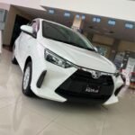SaveTikTokto_7494885108328025399_2 - Dyantransport White Toyota Agya GR Sport on a showroom floor, angled front view with glossy tiles and showroom signage in the background