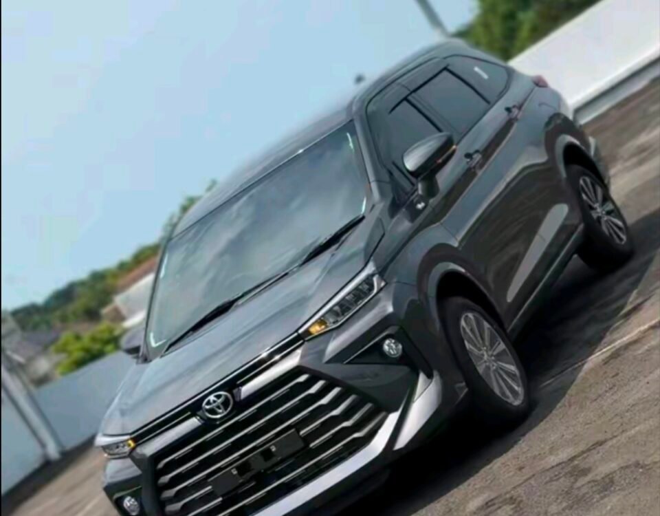 Gray SUV photographed from the front-left angle on a paved outdoor area under a blue sky.