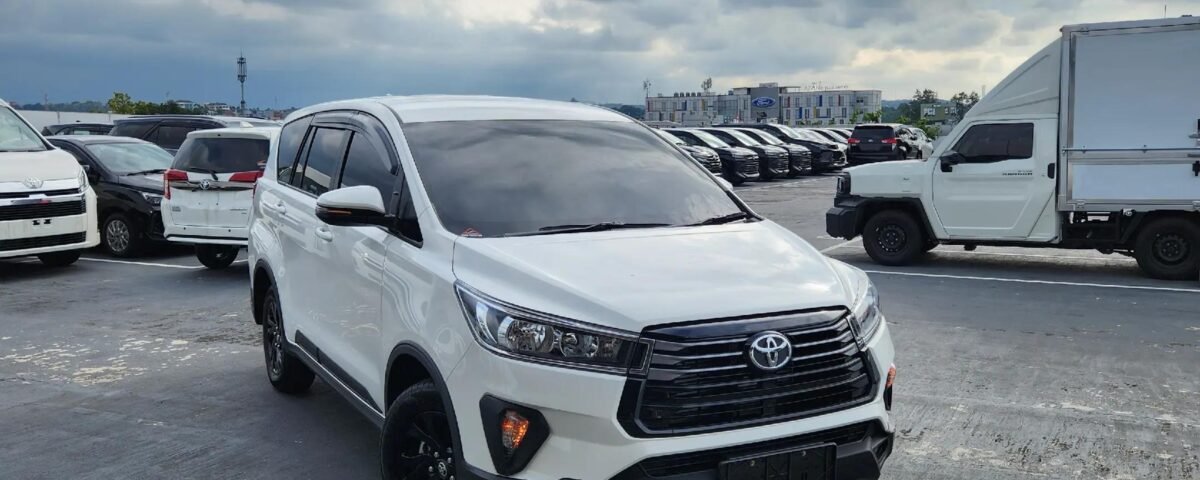 White Toyota SUV in a crowded parking lot under a cloudy sky.