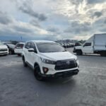 White Toyota SUV in a crowded parking lot under a cloudy sky.