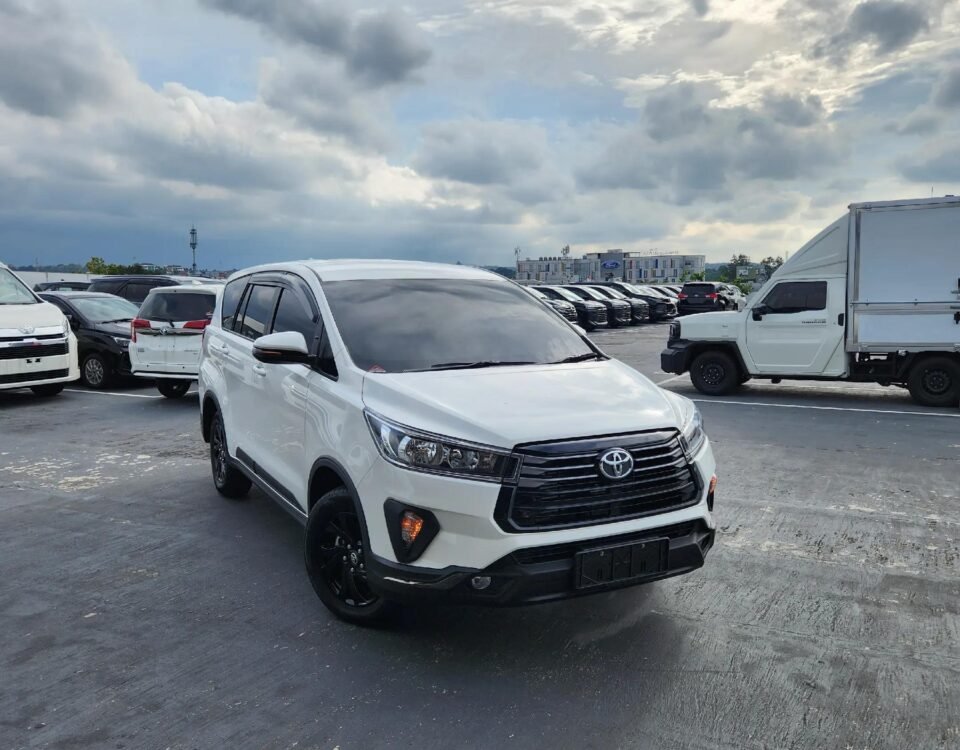 White Toyota SUV in a crowded parking lot under a cloudy sky.
