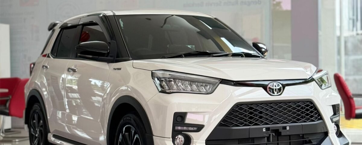 SaveTikTokto_7607337355426450696_1 - Dyantransport White Toyota SUV on a glossy showroom floor with red seating and glass walls behind it, angled to show front and side.