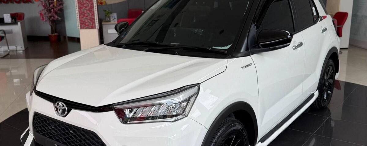 SaveTikTokto_7607337355426450696_2 - Dyantransport White Toyota SUV on a glossy showroom floor, front three-quarter view with black wheels and tinted windows, dealership interior in the background.