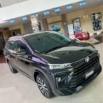 Black Toyota Avanza on display in a bright showroom, front three-quarter view with glossy finish.