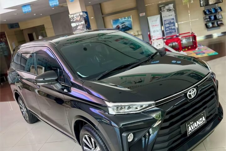 Black Toyota Avanza on display in a bright showroom, front three-quarter view with glossy finish.