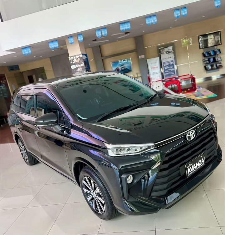 Black Toyota Avanza on display in a bright showroom, front three-quarter view with glossy finish.