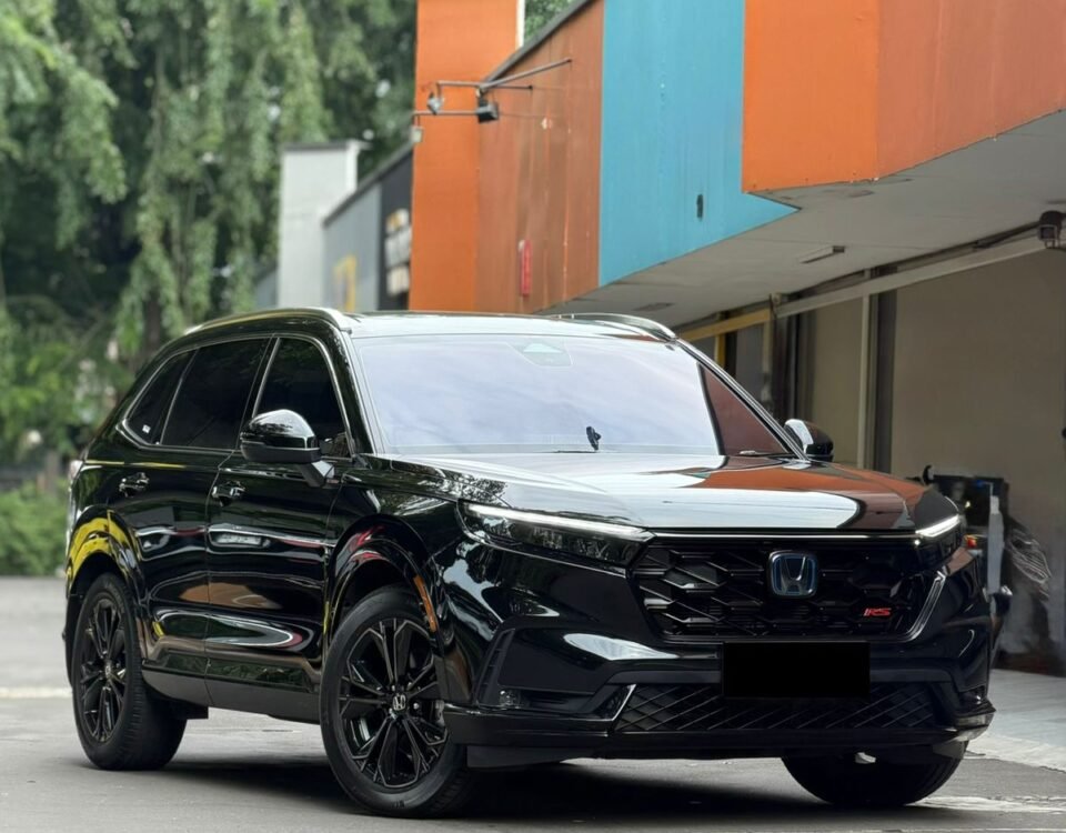 Black Honda SUV with glossy finish and large alloy wheels parked beside a colorful orange and teal building.