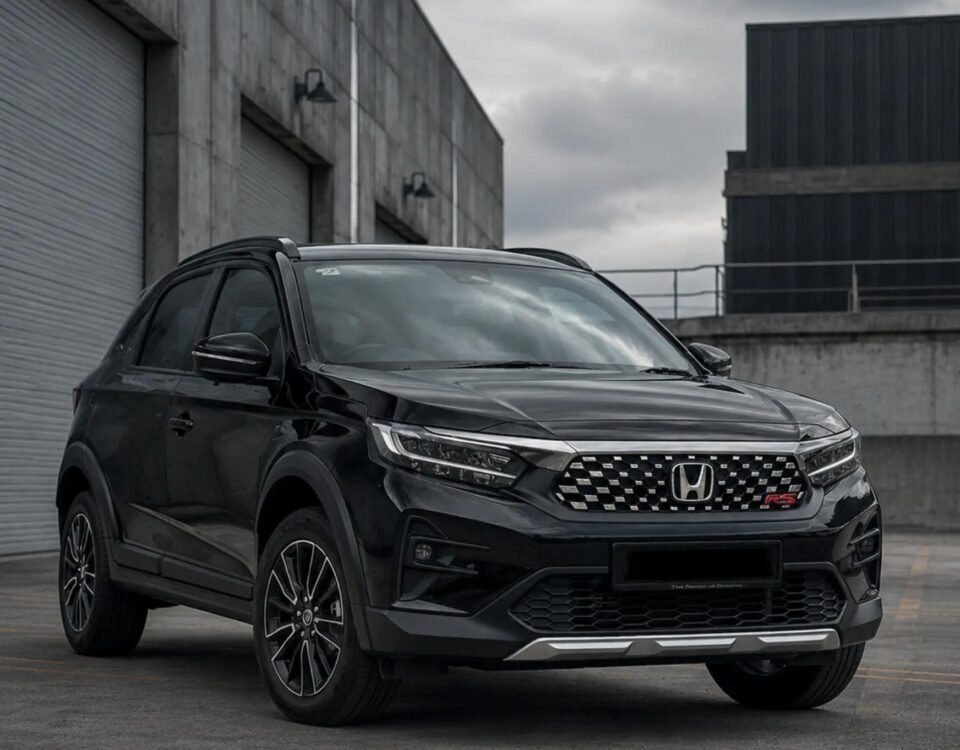 Front three-quarter view of a black Honda SUV parked in an industrial loading area with concrete walls and cloudy sky ahead of it.