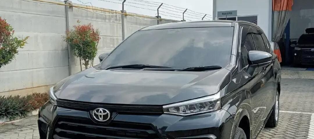 SaveTikTokto_7668299100755856648_3 - Dyantransport Front three-quarter view of a dark gray Toyota SUV parked in a lot near a service building with a barbed-wire fence behind it.
