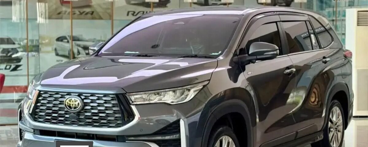 Gray Toyota SUV on a glossy showroom floor with glass walls and other cars in the background (front three-quarter view).