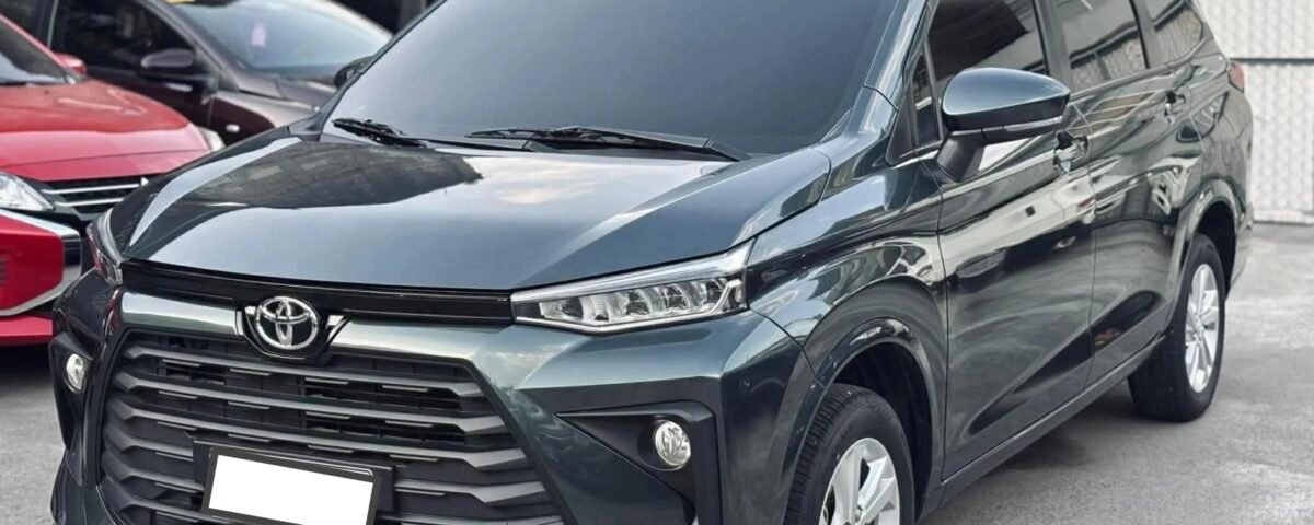 Gray Toyota SUV parked in a lot, showing the front grille and headlights with other cars in the background.