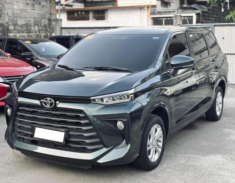 Gray Toyota SUV parked in a lot, showing the front grille and headlights with other cars in the background.