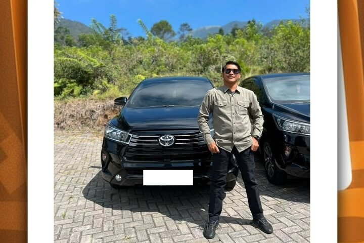 WhatsApp Image 2026-08-21 at 111059 1 - Dyantransport Man in a beige shirt and sunglasses posing in front of two black SUVs in a sunny outdoor lot with greenery behind him from a social post image.