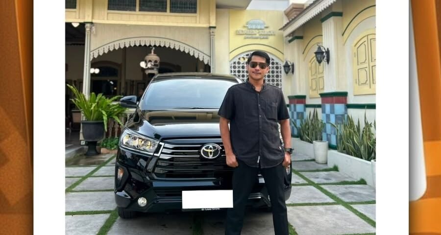 Man in dark shirt and sunglasses stands beside a black Toyota SUV in a driveway in front of a yellow house.