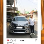 Man standing beside a silver Mitsubishi SUV on a street; promotional image for driver pickup service in Ungaran, Sleman route.