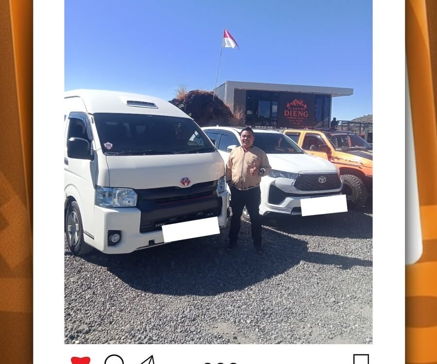 Driver from CV Berkah Dyantransport standing beside white van for pick-up service at Dieng route Pekalongan, with a company building in the background.