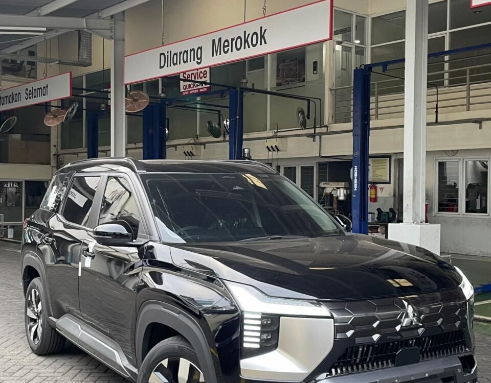 Black SUV parked inside a service bay with a 'Dilarang Merokok' (No Smoking) sign overhead, industrial lights above.