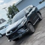 Front-side view of a dark Toyota SUV parked on a lot, angled for a dynamic shot, with the grille and emblem visible.