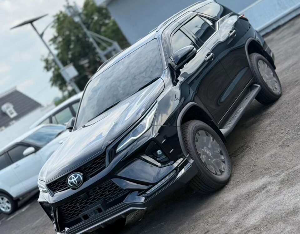 Front-side view of a dark Toyota SUV parked on a lot, angled for a dynamic shot, with the grille and emblem visible.