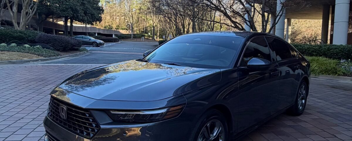 snaptik-app-7597857169412869389-slide-3 1 - Dyantransport Black Honda sedan parked on brick driveway in front of a modern glass-front building on a sunny day